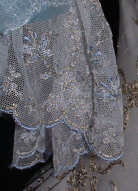 The boned stomacher style front panel has alternating bands of beaded and metallic lace. Like
all Rossetti gowns, it is fully lined throughout.