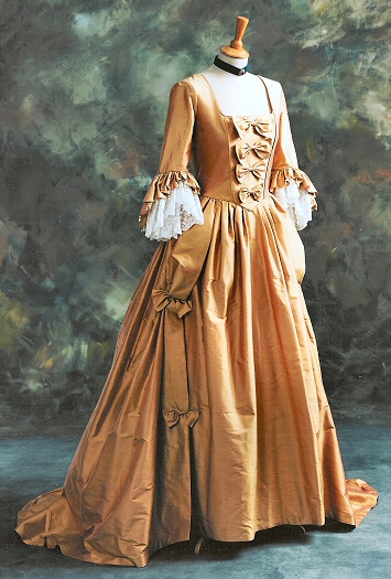 An eighteenth century style wedding dress shown in a pink/ gold silk dupion with ivory
lace sleeve flounces. The boned bodice has back lacing. Accurately made to customer's measurements